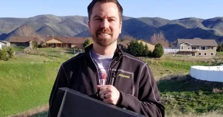 Clayton Johnson of Guys Outdoor Motorsports and Marine holding his giveaway prize outdoors